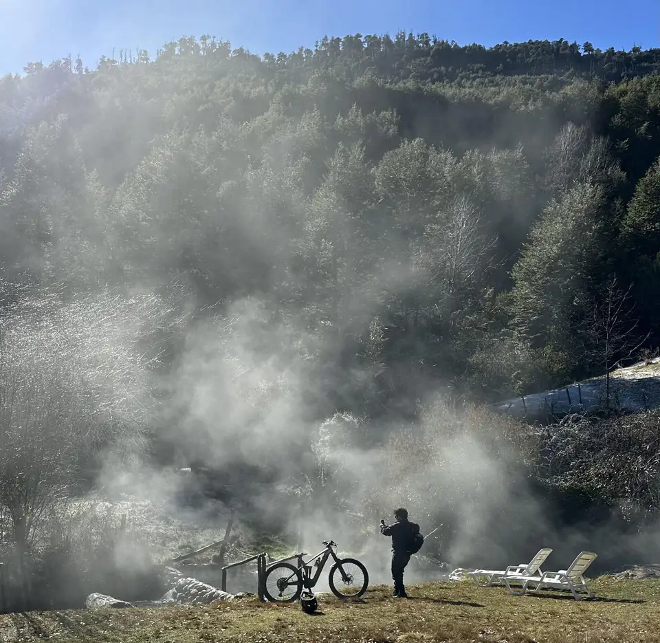 Vapor de termas naturales en el bosque, con una e-bike al borde